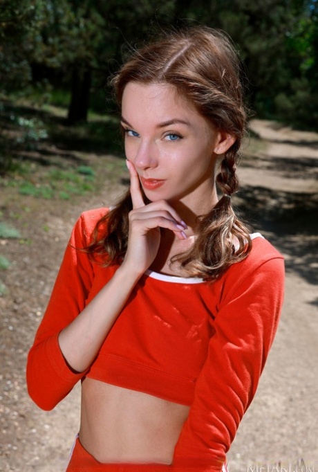 Sweet teen Josephine Jane wears braided pigtails while going nude in a forest